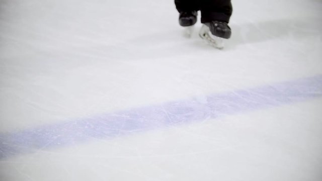 Hockey player rides away from the camera on the ice of a hockey field