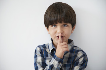 Kid with a secret with finger on lips
