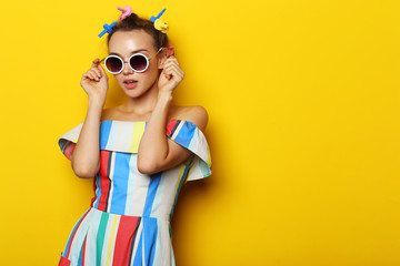 Fashion cool girl posing in sunglasses on yellow background.