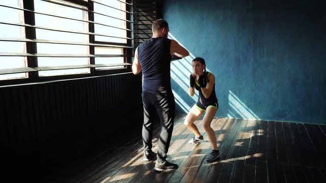fit white female boxer training with boxing coach at gym. Young slender brunette girl practicing with trainer. Wellness, healthy lifestyle, combat, motivation concept