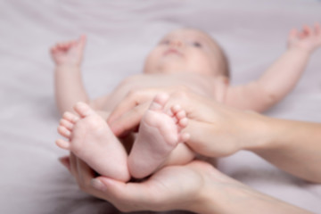 Baby legs in mother's hands. Blurred Background