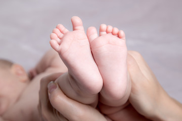 Obraz na płótnie Canvas Baby legs in mother's hands