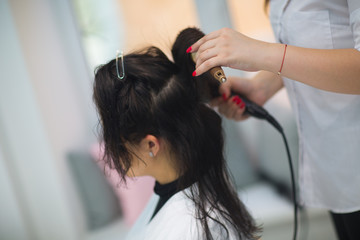 Brunette girl at the hairdresser doing styling