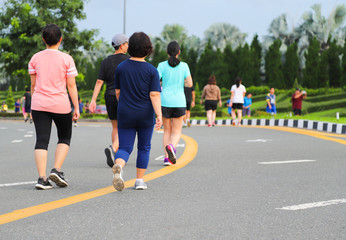 Closeup of a group of people walking and jogging on the road of public park.