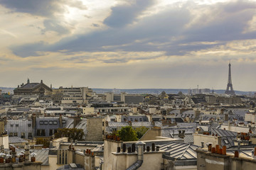 Naklejka premium The roofs of Paris and its chimneys under a clouds sky