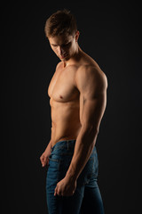 Fototapeta premium young, Strong bodybuilder with six packs. Bodybuilder flexes muscles against dark background