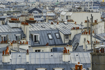 The roofs of Paris and its chimneys under a clouds sky