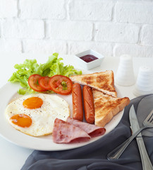 Morning breakfast, Fried egg, sausage and ham in white dish on table together light in the morning