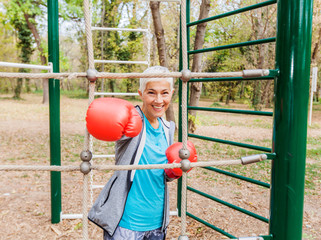 Obraz premium Happy Fit Senior Woman With Boxing Glove At Outdoor Gym