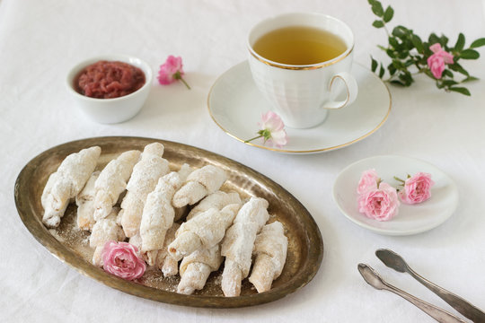 Traditional Romanian or Moldavian shortcake cookies with jam stuffing and a cup of tea on the light background.