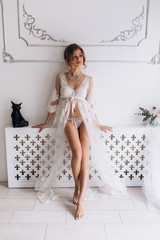Adorable woman in white lingerie poses before a luxury wall in a hotel
