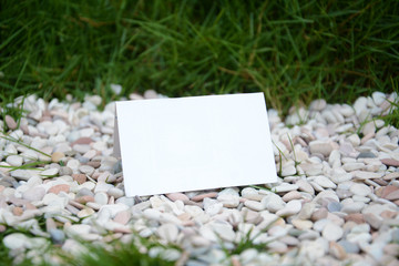 Blank white folded paper on the gravels and grasses