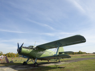 Fototapeta na wymiar View of classic airplane on the grassy airfield; aircraft after the flight with cases on propellers and other elements; green military aircraft on the runway; historical heritage of Russia