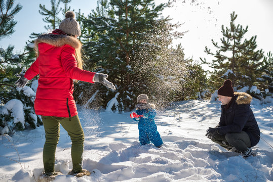 Father, mother and son play in snow in winter park. Happy winter holiday