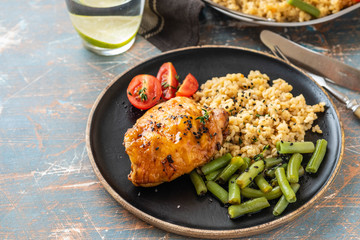 Grilled chicken thighs with bulgur, asparagus beans and tomatoes. Delicious lunch. Copy space.