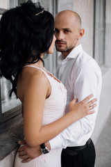Naklejka premium Handsome young bald headed man hugs with passion young brunette in pink evening dress