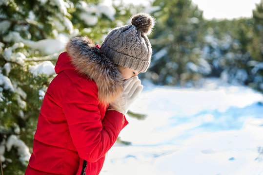 Warm dressed girl sneezes snot in winter park