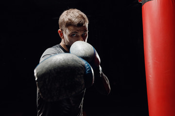 Male boxing in punching bag. Training Executes blows before fight.