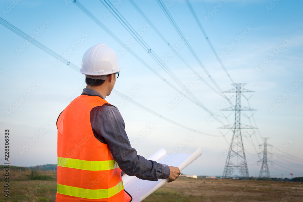 Wall mural engineering worker checking location site near to high voltage tower.