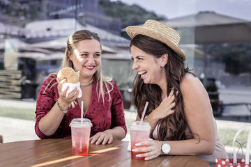 Positive emotions. Delighted joyful woman being in a great mood while sitting in the cafe with her friend