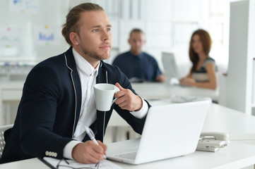 Portrait of businessman working at table with laptop