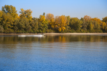 Motor boat with people on a lake, tree men, autumn