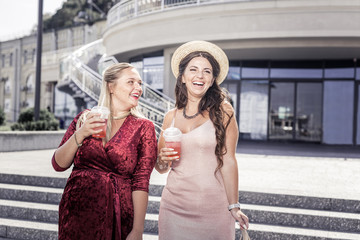 Favourite drinks. Cheerful delighted women laughing while enjoying their tasty lemonade