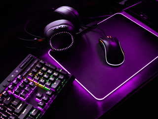 gamer workspace concept, top view a gaming gear, mouse, keyboard, joystick, headset, mobile joystick, in ear headphone and mouse pad on black table background.