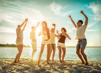 Friends funny dance on the beach under sunset sunlight. Sunny day - obrazy, fototapety, plakaty