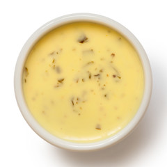 Creamy herb dressing in white ceramic condiment bowl isolated on white from above.