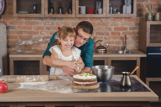 A girl with her father decorates a cake