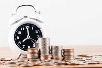 Stack of coins with clock for saving money concept