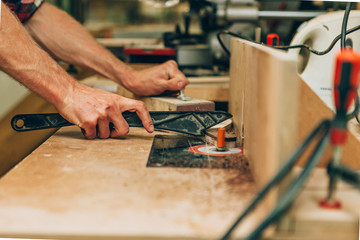 close up of the hands of a carpenter using a lathe