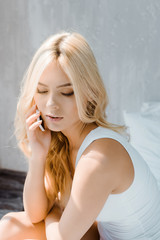 Obraz na płótnie Canvas attractive blonde girl in underwear talking by smartphone in bedroom