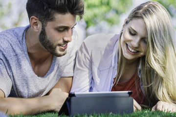 Couple using digital tablet in park