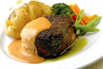 Filet mignon with mustard sauce accompanied by baked potato, carrot and broccoli.