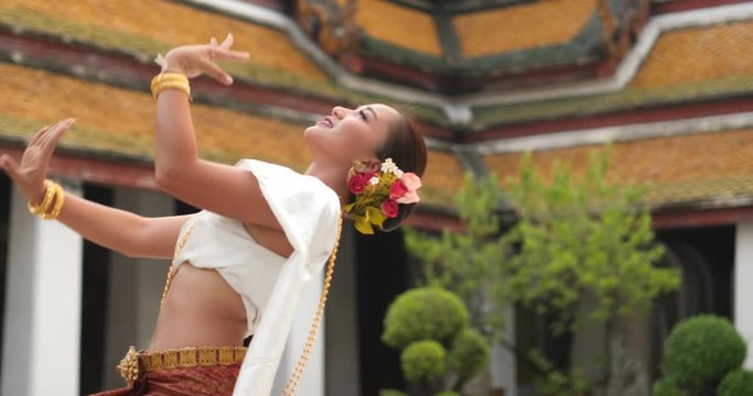 beautiful asian woman in thai traditional dress dancing traditional thai dance in Thai buddhist temple in bangkok wat suthat. outdoor next to temple