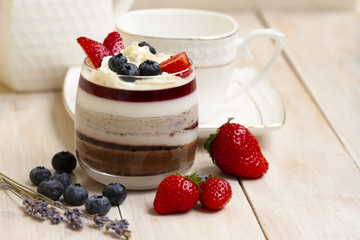Italian dessert - panna cotta with berries and berry jelly. Homemade berries aspic with different layers of chocolate, milk, cream, berry with fresh strawberries and blueberries