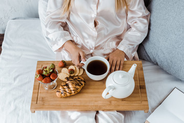 cropped image of woman in pajamas having breakfast in bed