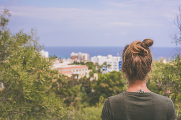 Obraz premium A woman stares into the distance to the sea horizon and the city in front of him