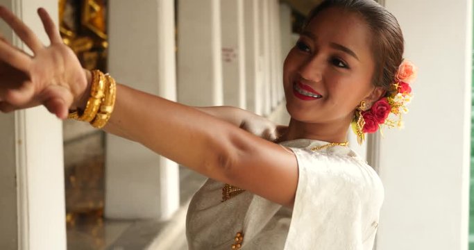 beautiful asian woman in thai traditional dress dancing traditional thai dance in Thai buddhist temple in bangkok wat suthat. outdoor next to temple