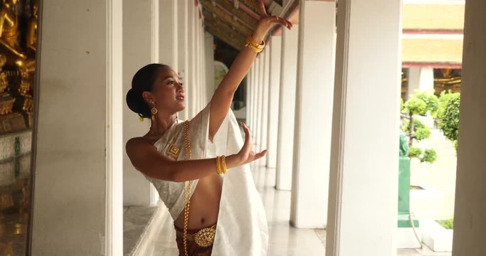 beautiful asian woman in thai traditional dress dancing traditional thai dance in Thai buddhist temple in bangkok wat suthat. outdoor next to temple