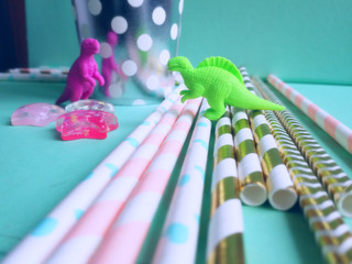 Colorful mint, pink and golden drinking straws for beverages with dinosaur toys. Party theme...