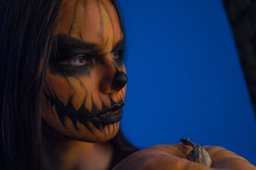 Close-up portrait of a girl with a terrible dead man mask on a dark background. Halloween Holiday