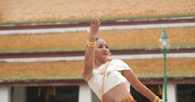 beautiful asian woman in thai traditional dress dancing traditional thai dance in Thai buddhist temple in bangkok wat suthat. outdoor next to temple