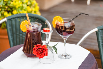 Jug and glass with delicious refreshing sangria wine on table in cafe, outdoors