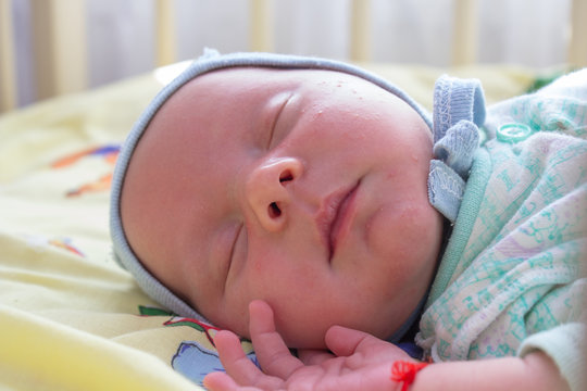 baby sleeps on the side,Baby sleeping with open arms and without pacifier in a cradle