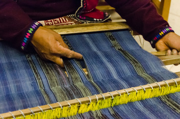 A Peruvian man weaves a loom inside of a workshop, Cusco, Peru