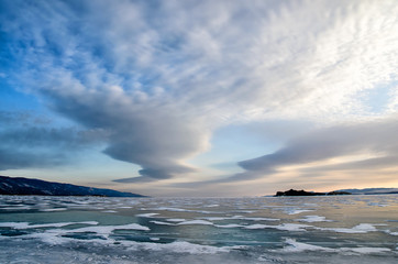 Frozen Lake Baikal. Beautiful stratus clouds over the ice surface on a frosty day.