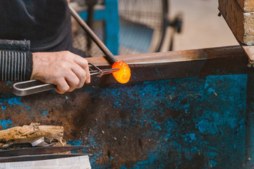 Artist Man Hands Closeup Working on a shape of a Hot Glass in workshop